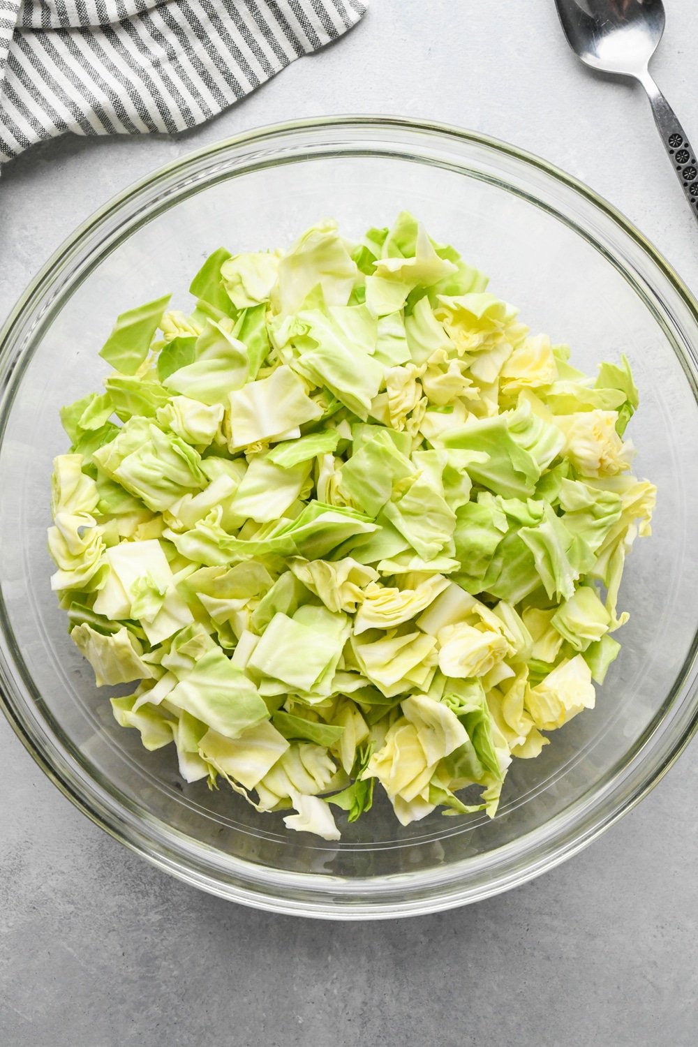 How to make chopped green cabbage salad: Chopped green cabbage in a large glass bowl. 