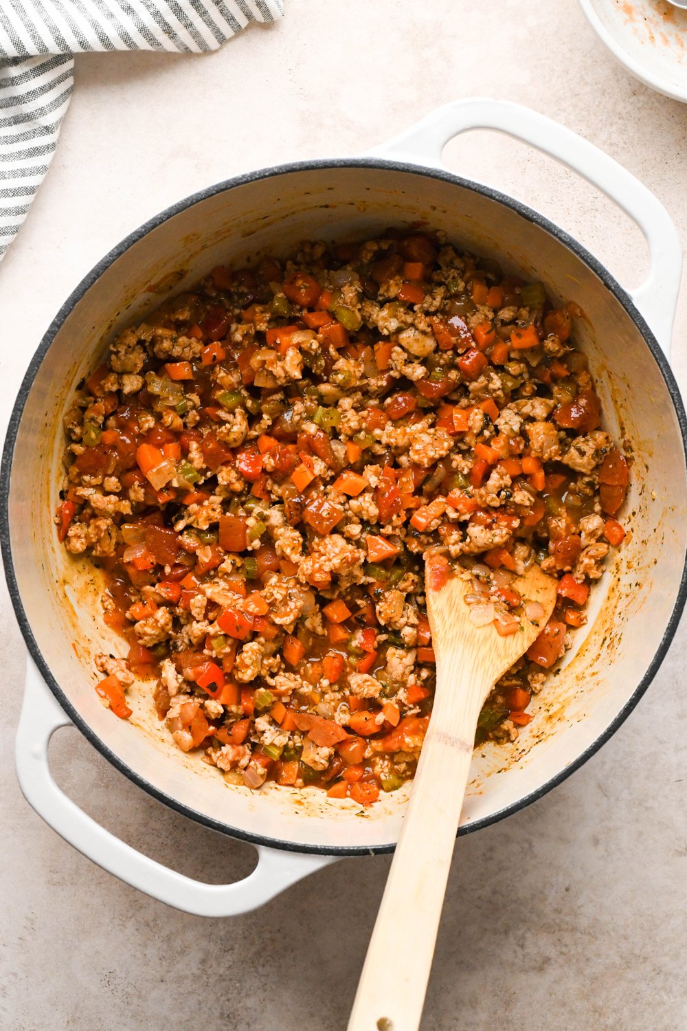 How to make Cashew Cream Buffalo Chicken Chili Made with Ground Chicken: Diced fire roasted tomatoes and buffalo sauce added to the soup pot with chicken, veggies, and spices, after stirring together to combine.