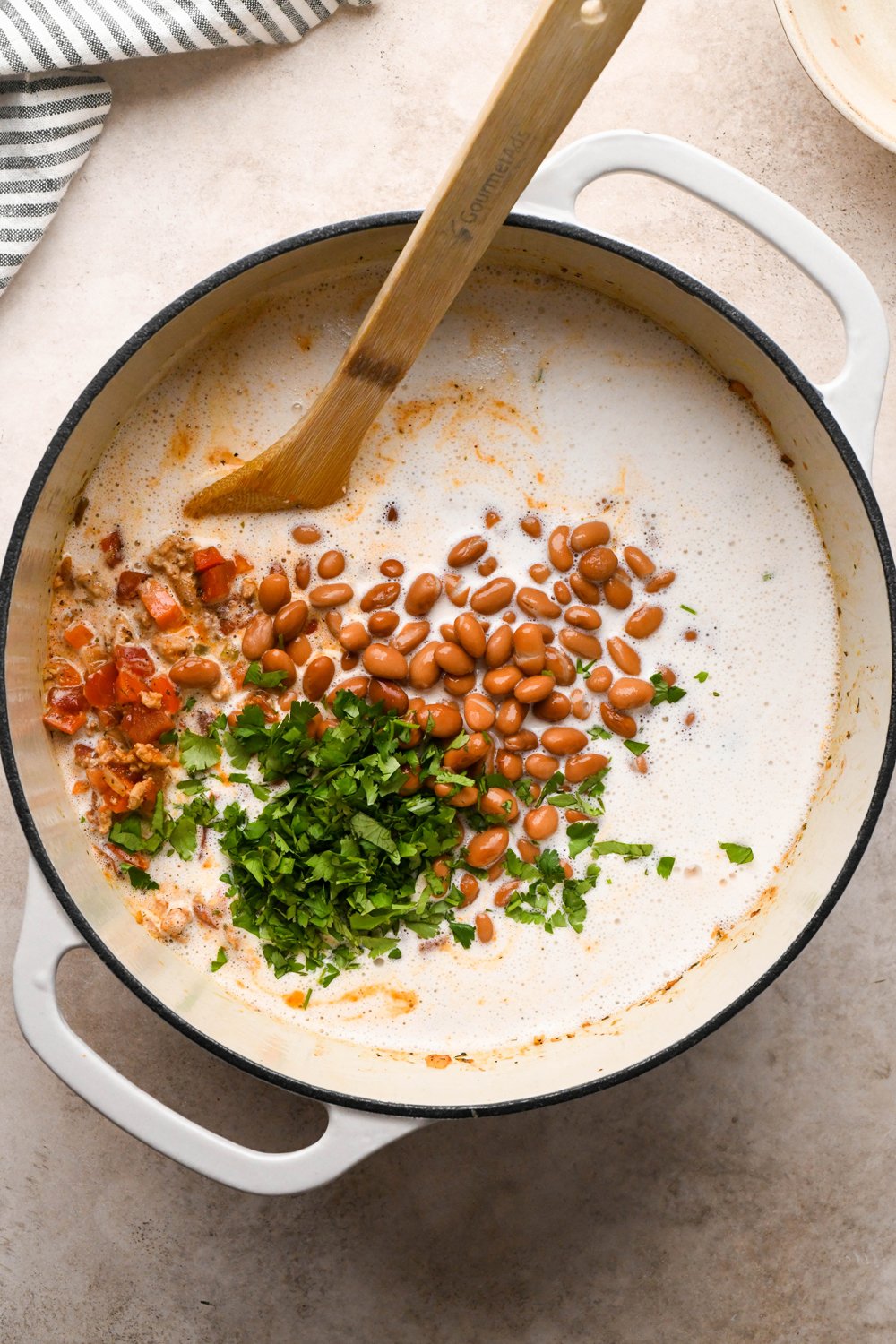 How to make Cashew Cream Buffalo Chicken Chili Made with Ground Chicken: Cashew cream in the pot of soup with drained beans and chopped cilantro added but not yet stirred. 