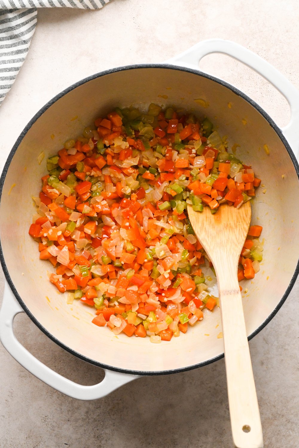 How to make Cashew Cream Buffalo Chicken Chili Made with Ground Chicken: Raw diced onion, carrots, celery, bell pepper, and garlic in a soup pot with olive oil after cooking.