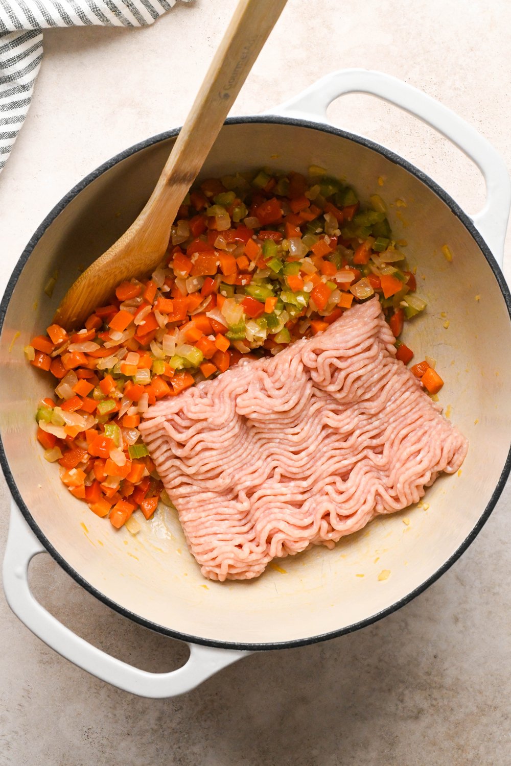 How to make Cashew Cream Buffalo Chicken Chili Made with Ground Chicken: Veggies moved aside to make room for raw ground chicken breast in the soup pot.