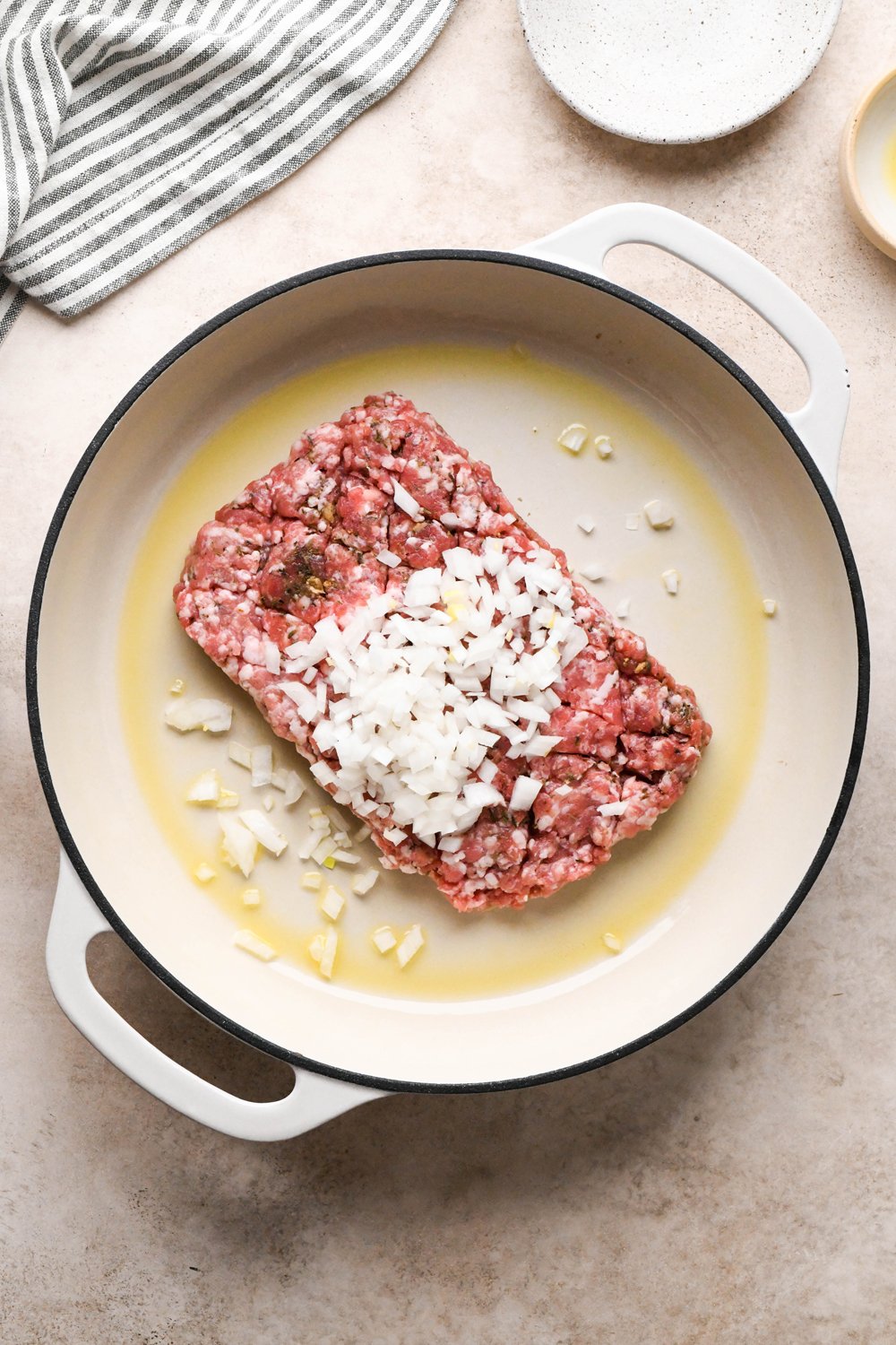 How to make Gluten Free Sausage Gravy: Breakfast sausage and diced onions in a large ceramic skillet before cooking.
