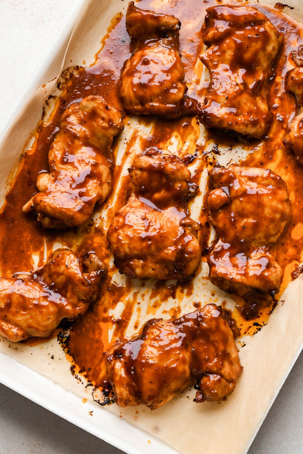 How to make BBQ Chicken Rice Bowls: Marinated chicken thighs on a baking sheet before broiling to caramelize.