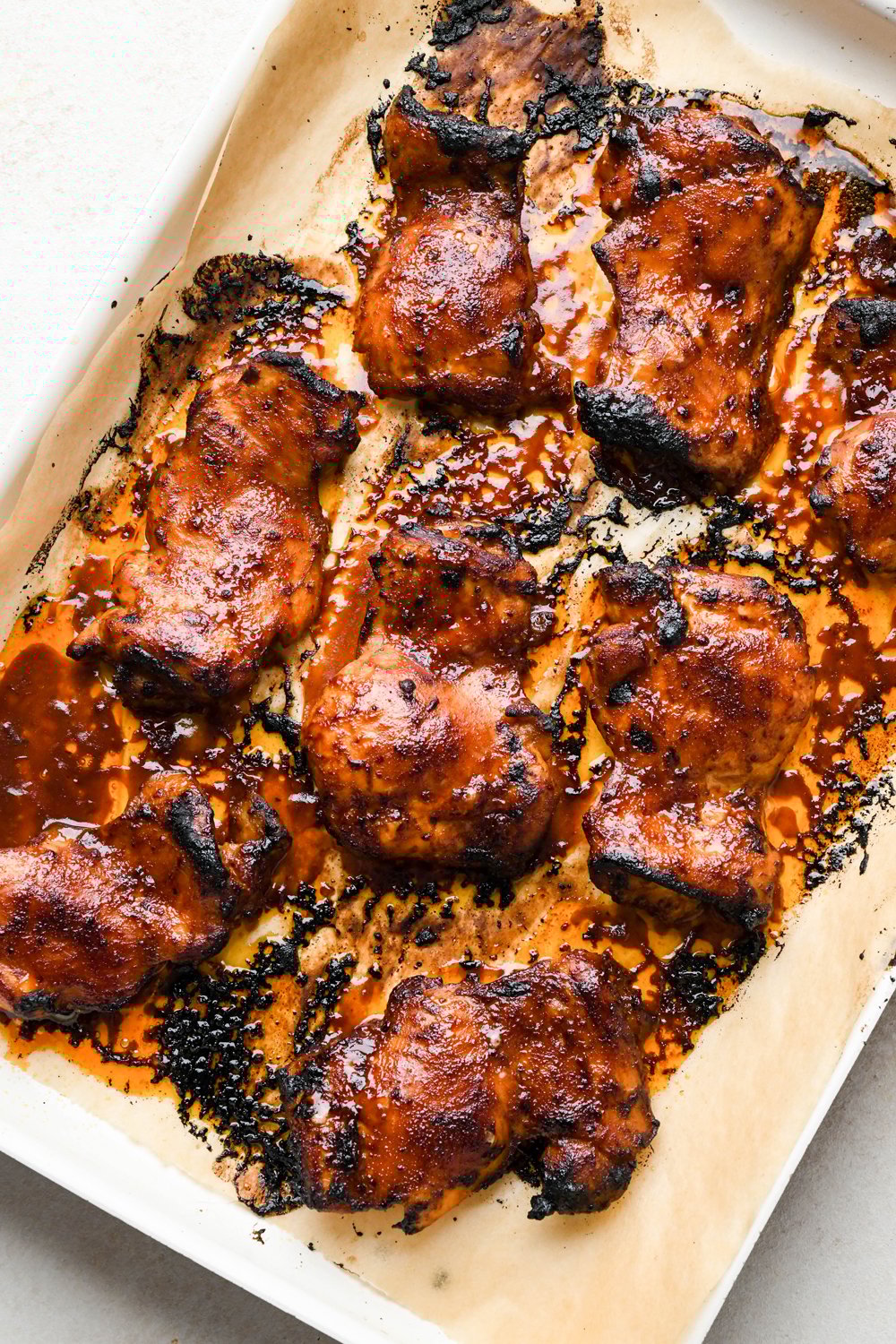 How to make BBQ Chicken Rice Bowls: Marinated chicken thighs on a baking sheet after broiling to caramelize.