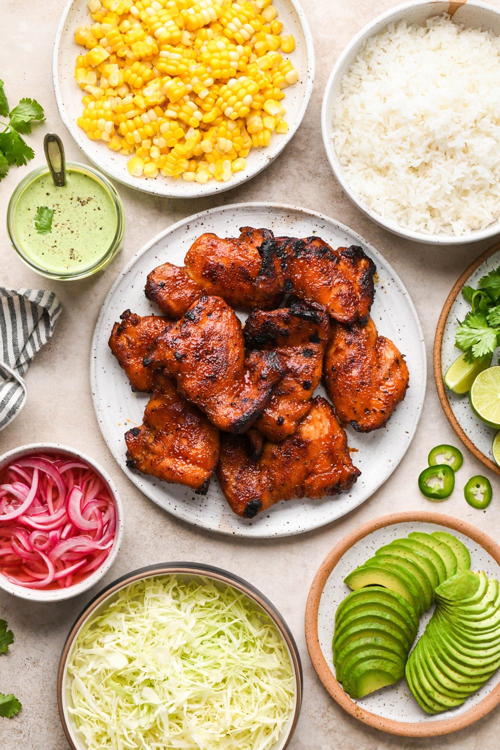 Ingredients for BBQ Chicken Rice Bowls in various ceramics on a light creamy brown colored background.