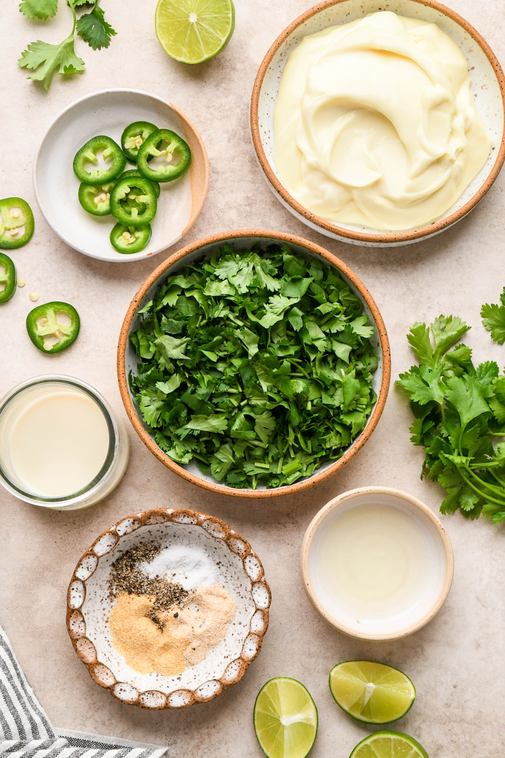 Ingredients for dairy free cilantro ranch in various ceramics on a light brown background.