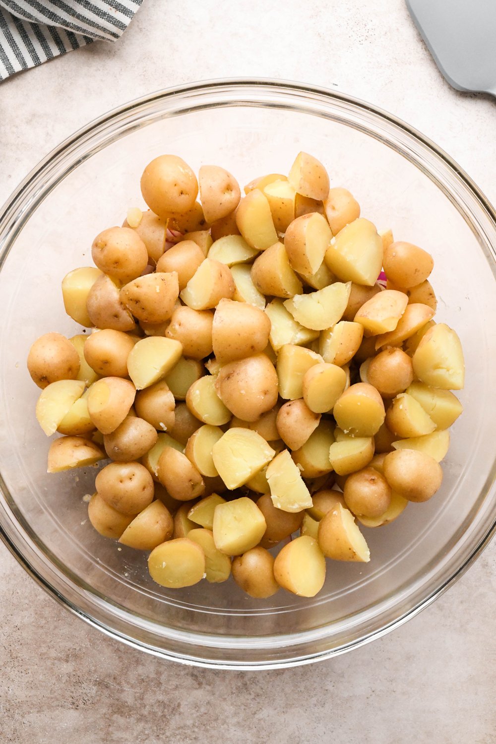 How to make Dill Pickle Potato Salad with Creamy Dill Dressing: Cooked and cooled baby potatoes in the large mixing bowl with the lightly pickled red onions and the base of the dressing, before tossing to combine.