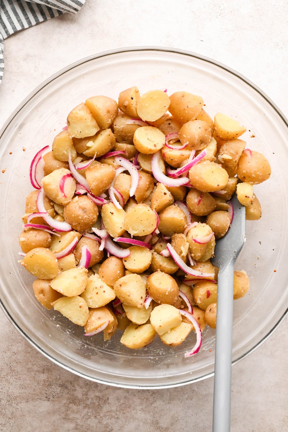 How to make Dill Pickle Potato Salad with Creamy Dill Dressing: Cooked and cooled baby potatoes in the large mixing bowl with the lightly pickled red onions and the base of the dressing, after tossing to combine.