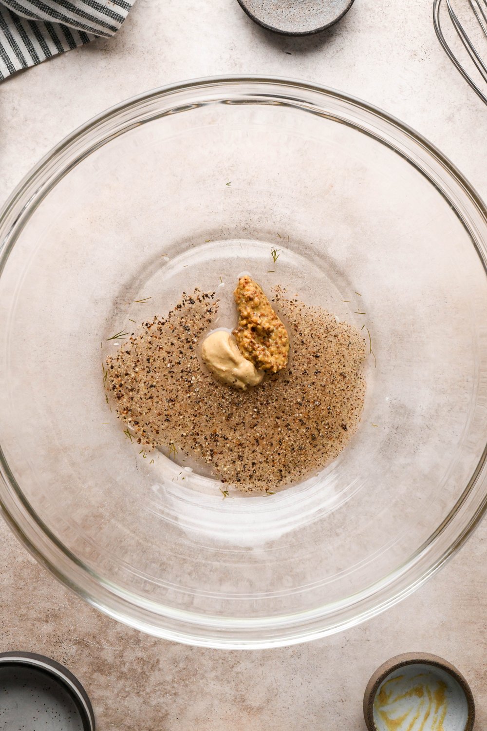 How to make Dill Pickle Potato Salad with Creamy Dill Dressing: A large glass bowl with pickle brine, white vinegar, dijon mustard, and grainy mustard, before whisking together.