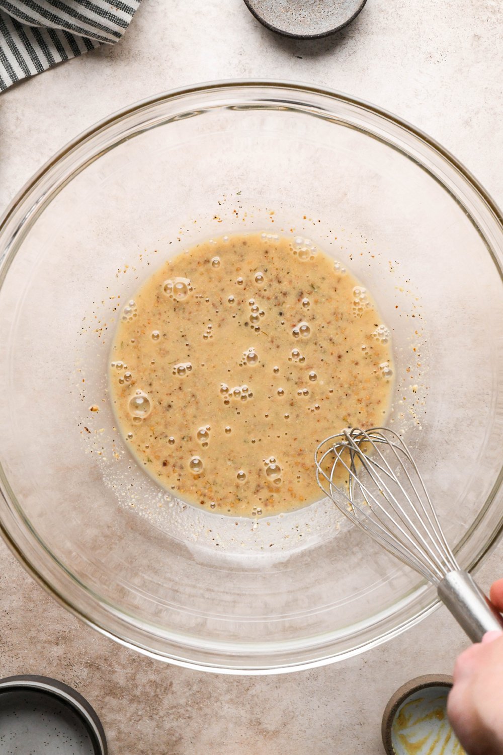 How to make Dill Pickle Potato Salad with Creamy Dill Dressing: A large glass bowl with pickle brine, white vinegar, dijon mustard, and grainy mustard, after whisking together.
