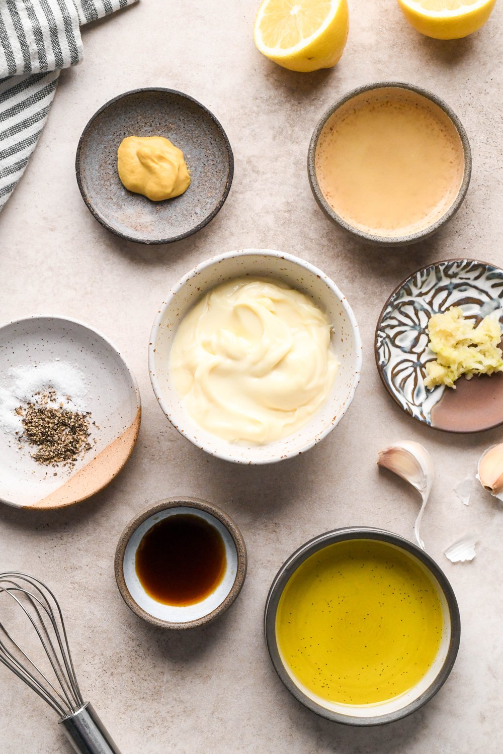 Ingredients for homemade dairy free Caesar salad dressing in various ceramics on a light brown creamy background.