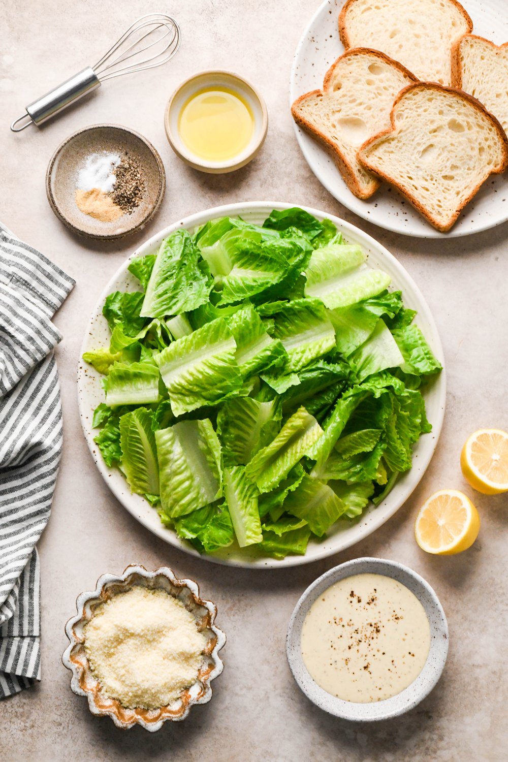 Ingredients for Caesar salad with gluten free breadcrumbs in various ceramics on a light brown creamy background.