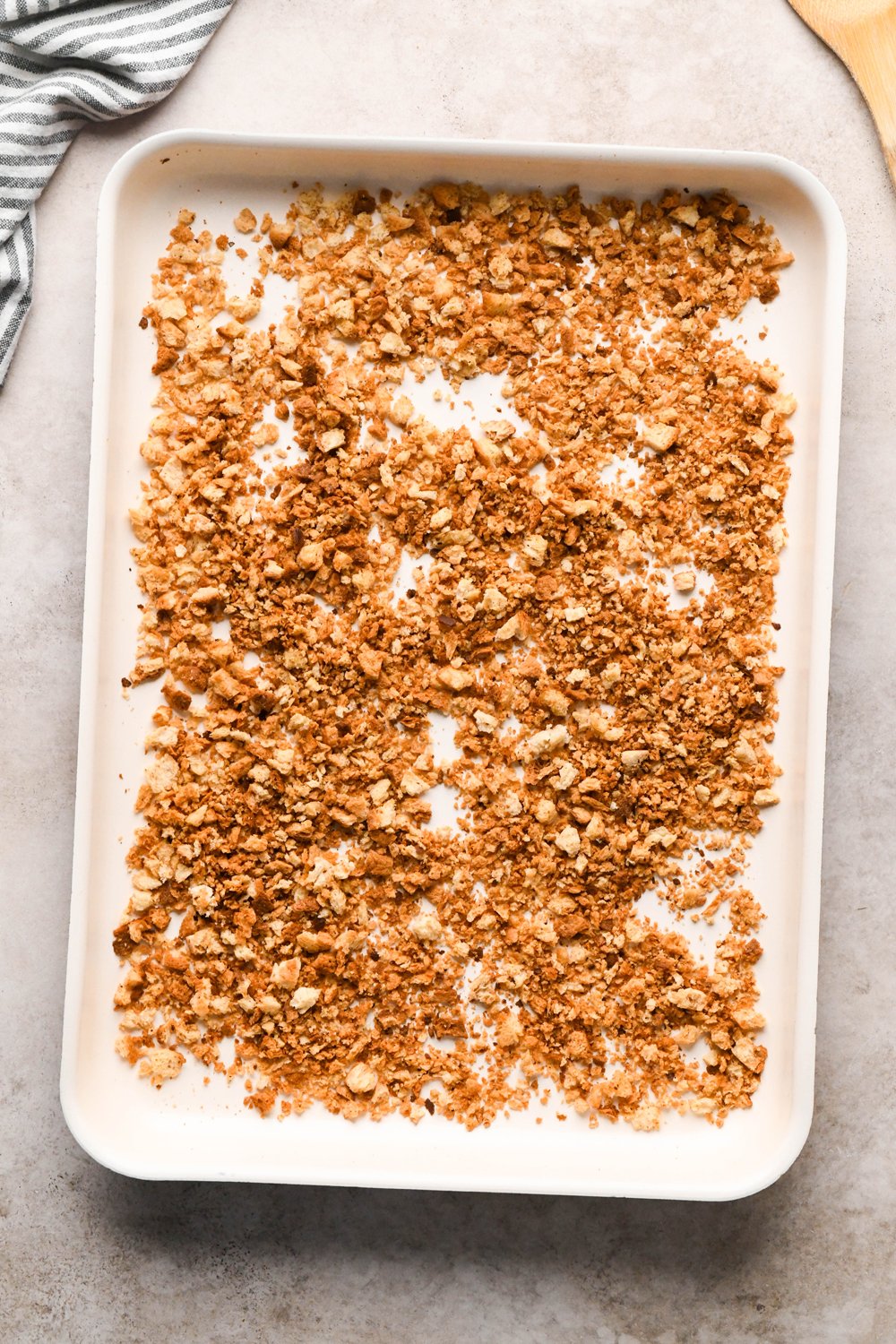 How to make a Caesar Salad with gluten free breadcrumbs: Breadcrumbs on a white baking sheet after baking until golden brown. 
