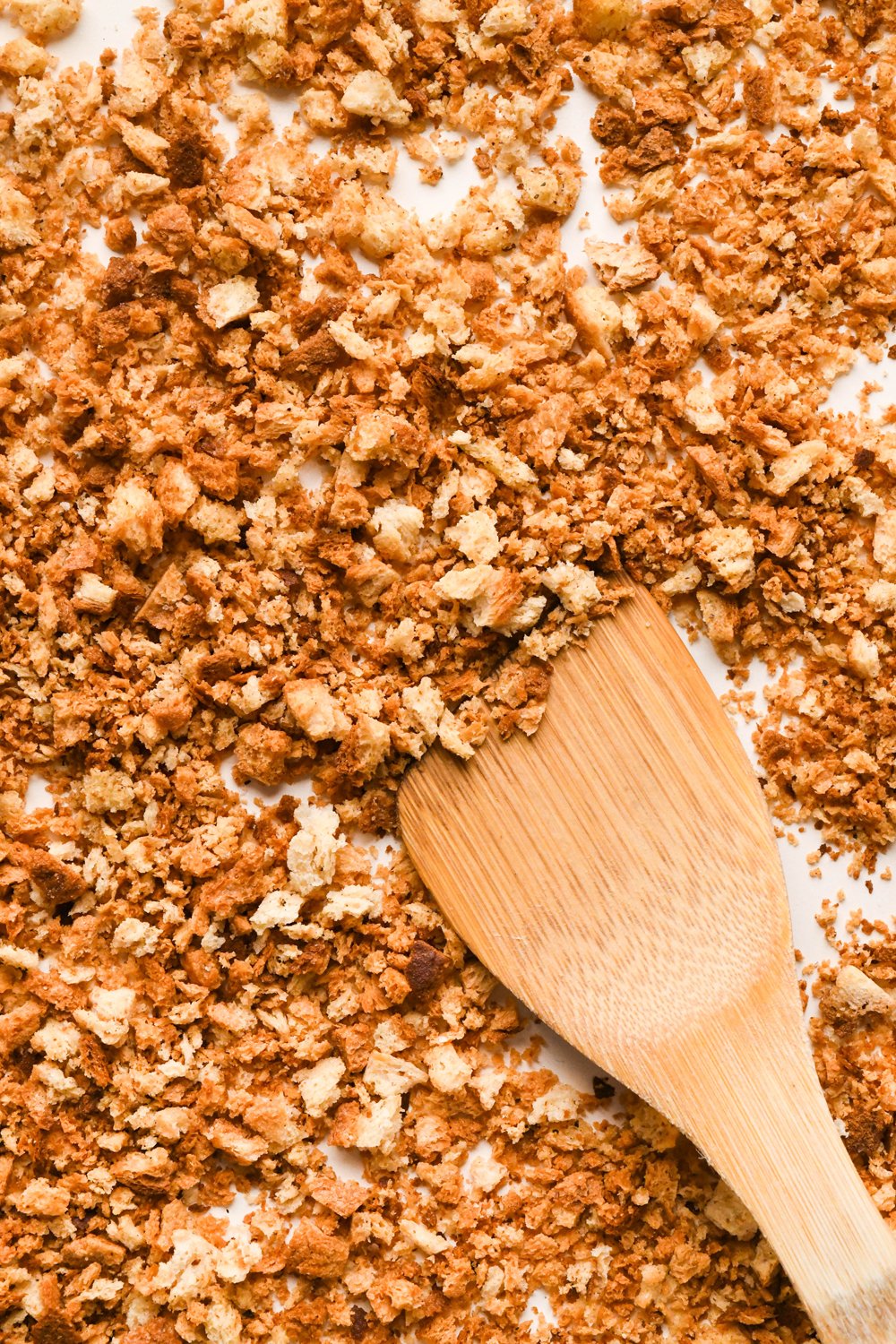 How to make a Caesar Salad with gluten free breadcrumbs: A wooden spatula showing the up-close texture of the baked breadcrumbs.