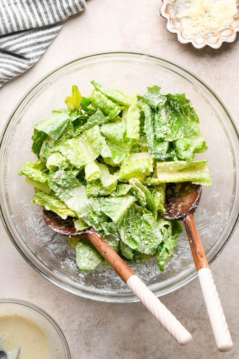 How to make a Caesar Salad with gluten free breadcrumbs: Caesar salad in large glass bowl after tossing with the dressing and the grated Parmesan. 