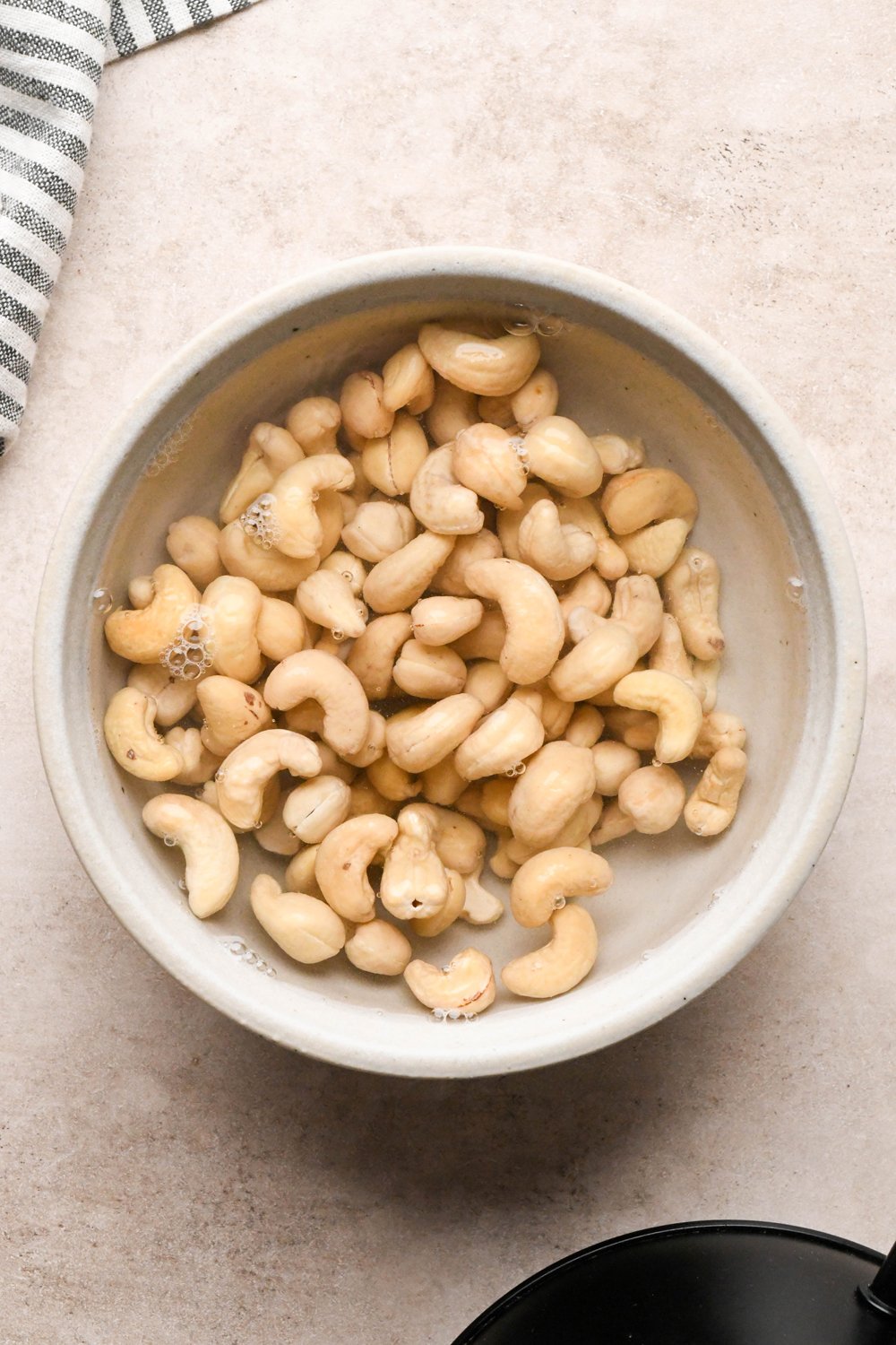 How to make Chicken and Broccoli Soup: Cashews soaking in hot water, in a small ceramic grey bowl.  