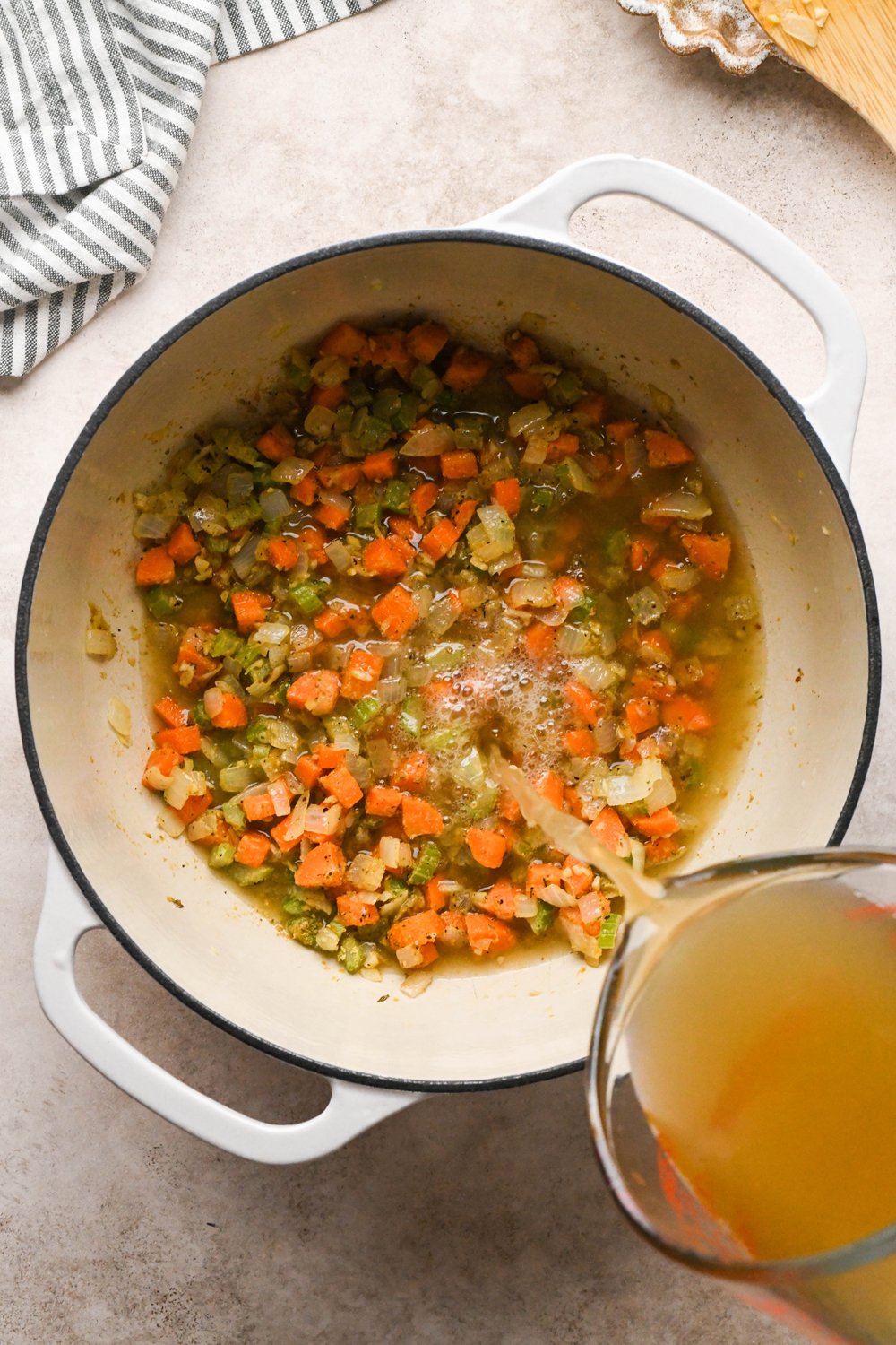 How to make Chicken and Broccoli Soup: A hand pouring chicken broth into the soup pot. 