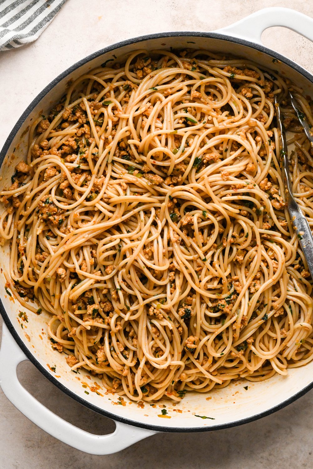 How to make garlic scallion noodles: Cooked gluten free spaghetti noodles added to the skillet with the ground chicken sauce, after tossing to combine.