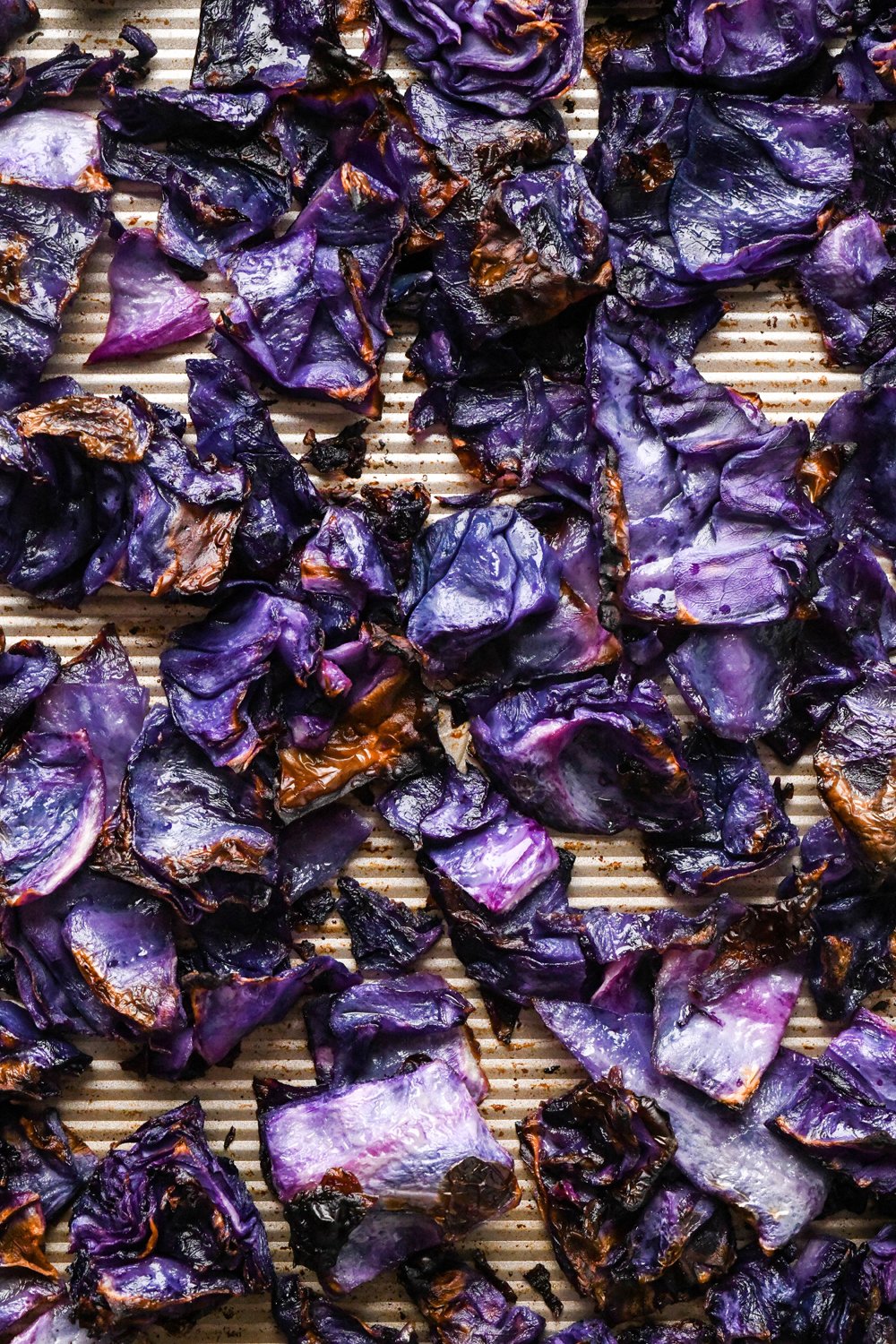 How to make Roasted Chopped Red Cabbage with Olive Oil: Cabbage pieces after they have been roasted. The cabbage appears soft and tender, with crispy edges. This image shows a close up of the roasted cabbage, to display the texture of each piece.