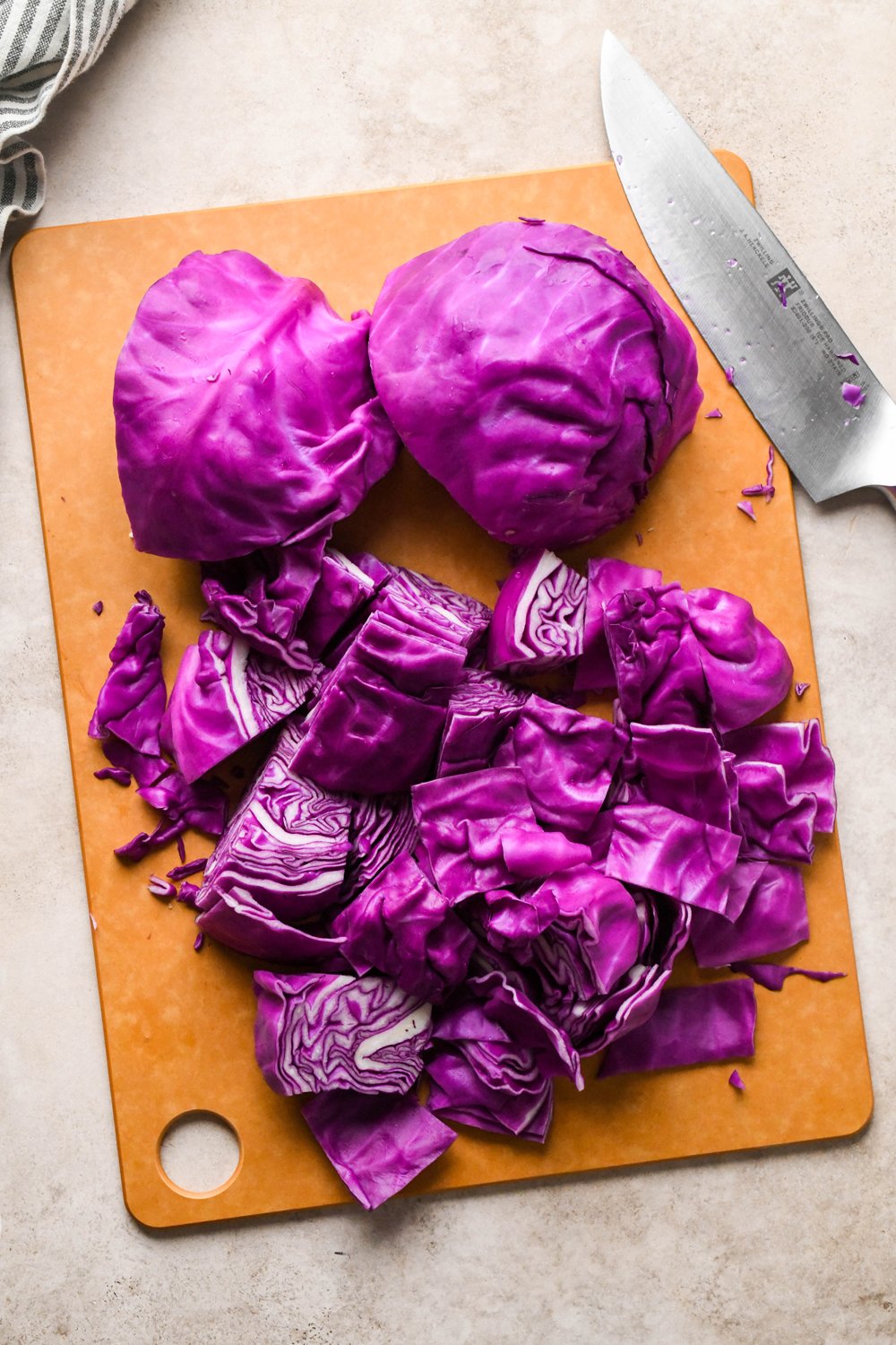 How to make Roasted Chopped Red Cabbage with Olive Oil: Cabbage quarters without the stems have been flipped onto their flat side, and two of the four quarters have been chopped into bite-sized pieces.