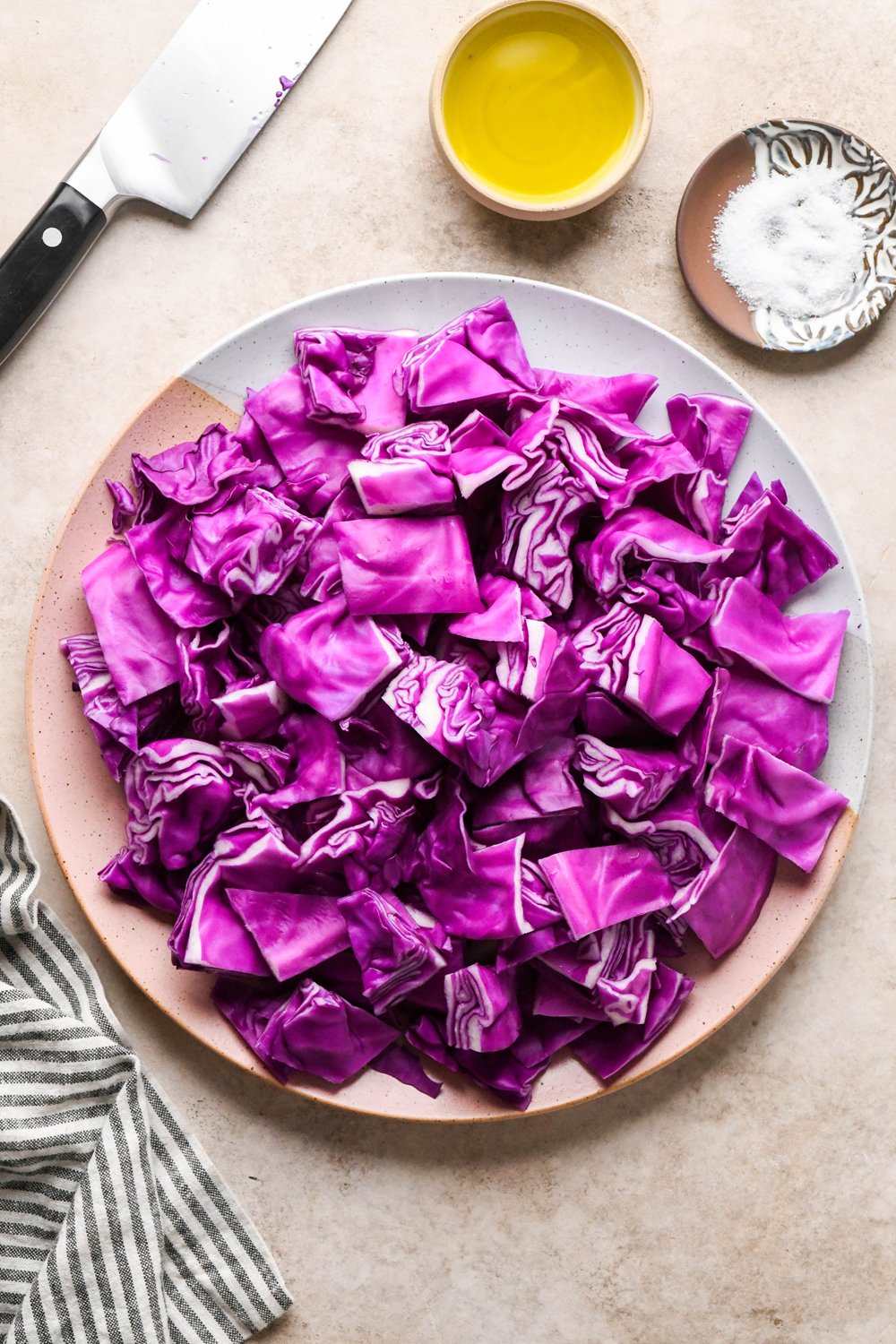 Ingredients for roasted red cabbage on various ceramics on a light creamy brown background.