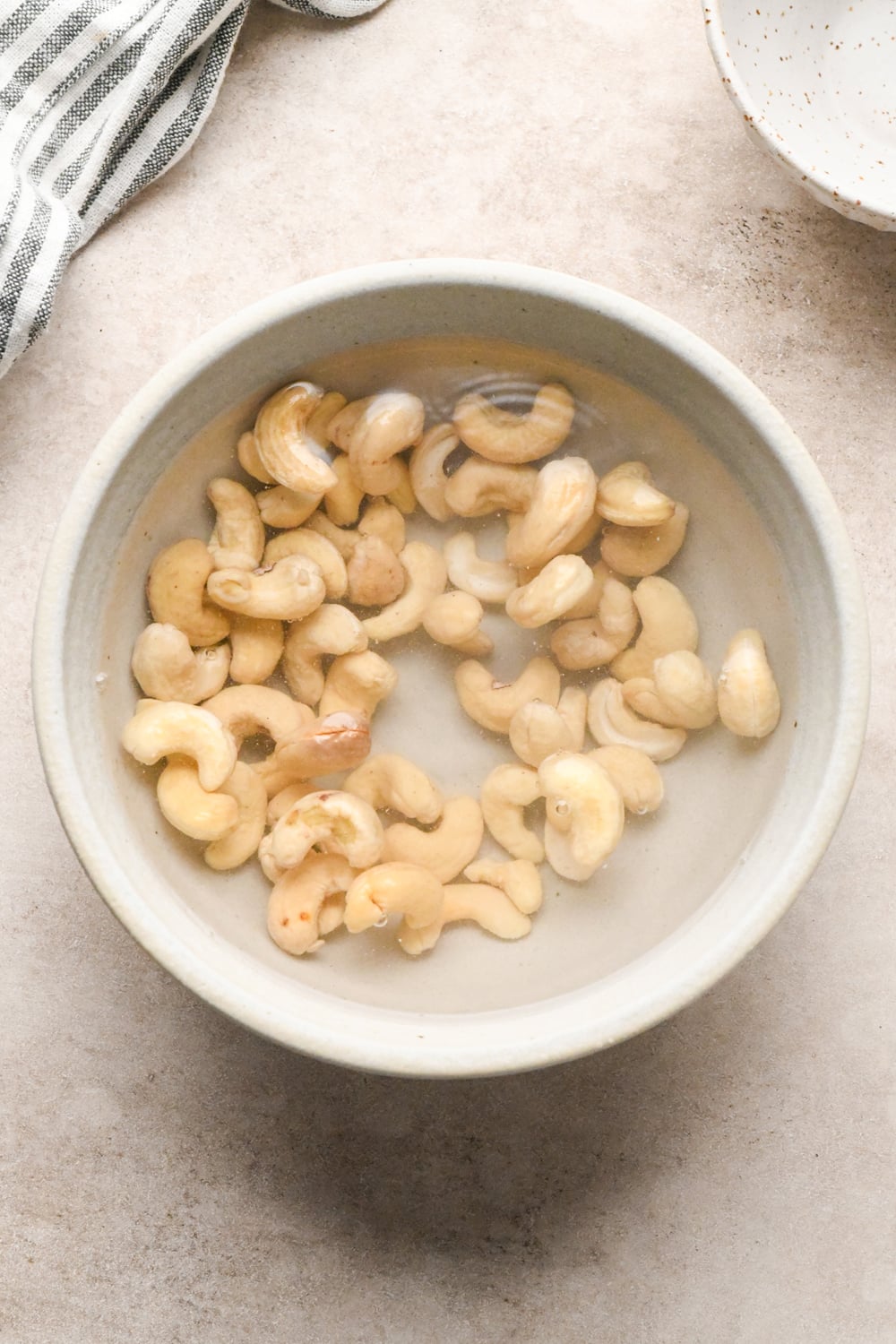 Raw cashews soaking in a bowl of water.